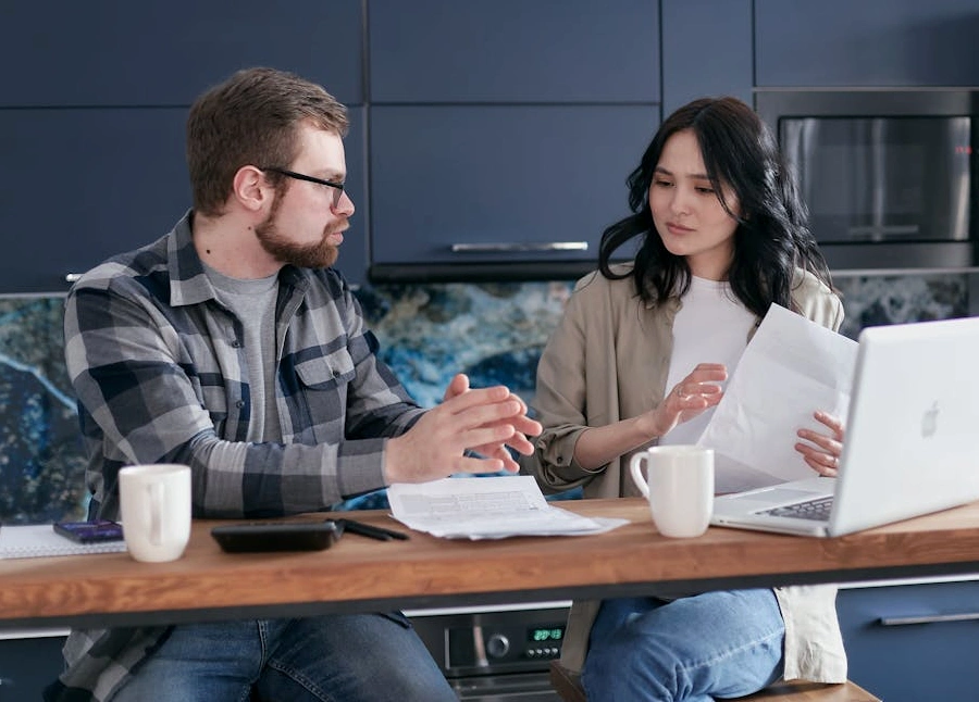 Una scrivania ordinata con un libro di finanza, un laptop e una tazza di caffè.